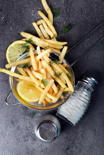 Patatas fritas con limón y sal en tamiz sobre mesa