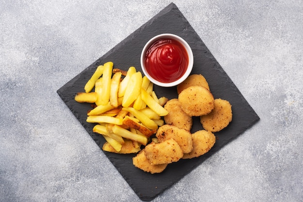 Patatas fritas y nuggets de pollo con salsa de tomate ketchup.