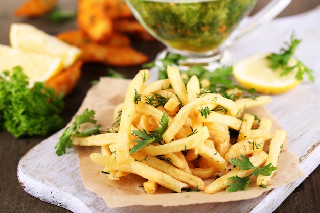 Patatas fritas en papel de rastreo a bordo en una mesa de madera