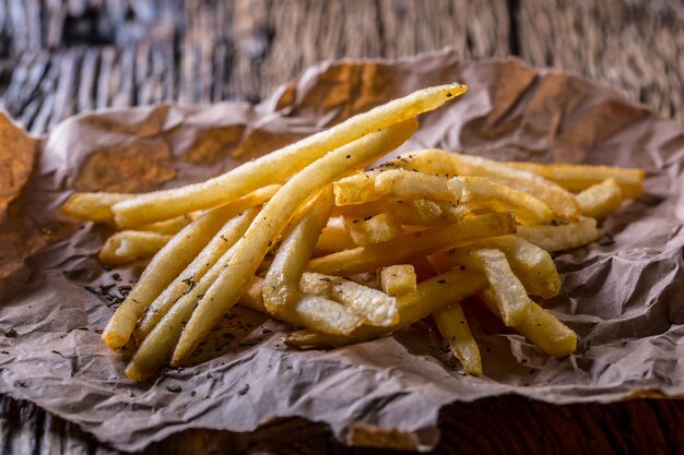 Patatas fritas patatas fritas doradas con sal y hierbas secas en tablero de madera