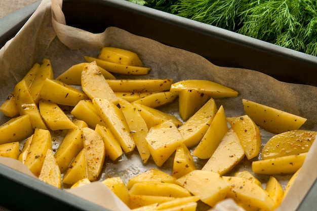 Patatas fritas rebanadas en papel de hornear y eneldo verde