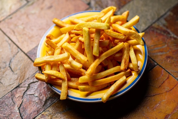 Patatas fritas recién cocinadas en un plato sobre fondo de piedra