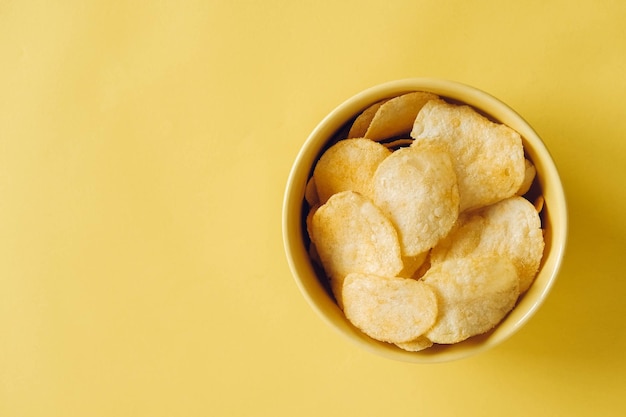 Patatas fritas en un recipiente amarillo sobre un fondo amarillo. Vista superior. Copiar, espacio vacío para texto