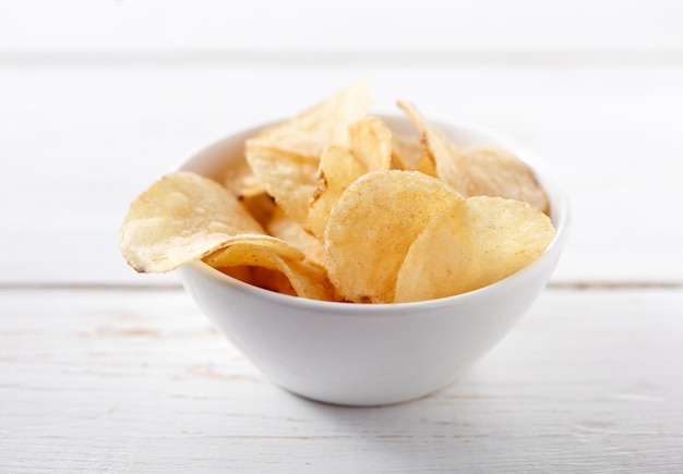 Patatas fritas en un recipiente sobre fondo blanco.