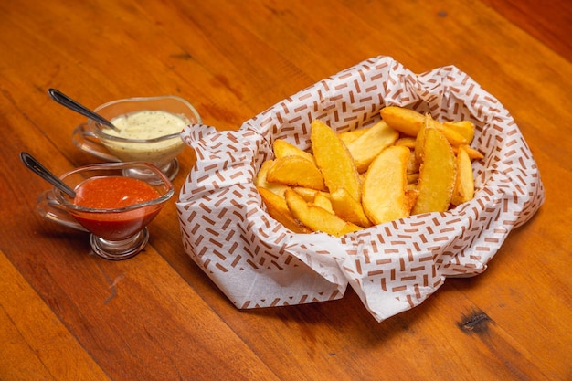 Patatas fritas rústicas, un aperitivo típico brasileño servido con mayonesa y salsa picante