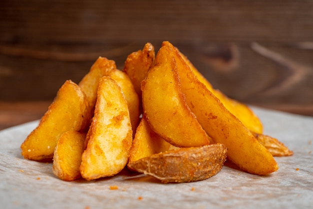 Patatas fritas rústicas sobre papel y fondo de madera.