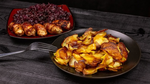 Patatas fritas y salchichas caseras a la parrilla o chevapchichi con col lombarda agria guisada sobre un fondo rústico de madera. Vista superior.