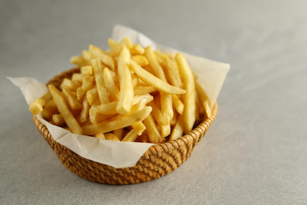 Patatas fritas con salsa en un plato de madera aislado con fondo gris