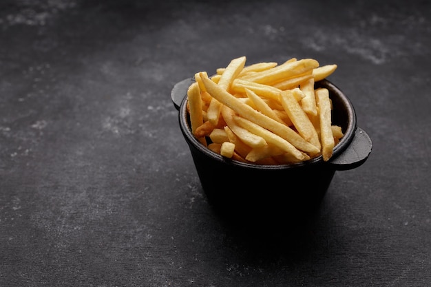 Patatas fritas sobre un fondo oscuro con espacio para texto