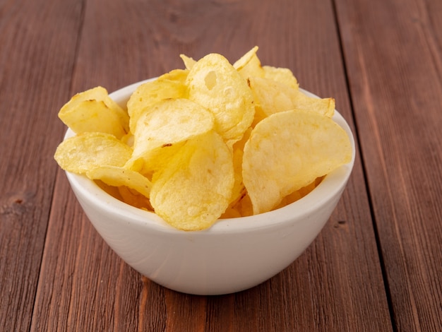 Patatas fritas en un tazón blanco sobre mesa de madera marrón