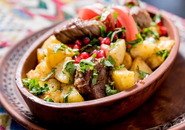 Patatas fritas con trozos de carne en una cazuela de barro. Cocina europea.