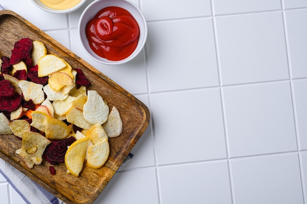 Patatas fritas de verduras de raíz sobre fondo de mesa de baldosas cuadradas de cerámica blanca vista superior plana con espacio de copia para texto