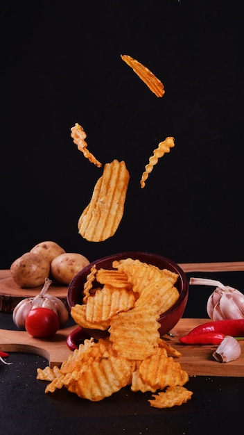 Patatas fritas voladoras en un cuenco de madera sobre un fondo negro.