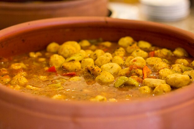 Patatas guisadas con verduras en una gran sartén de barro.