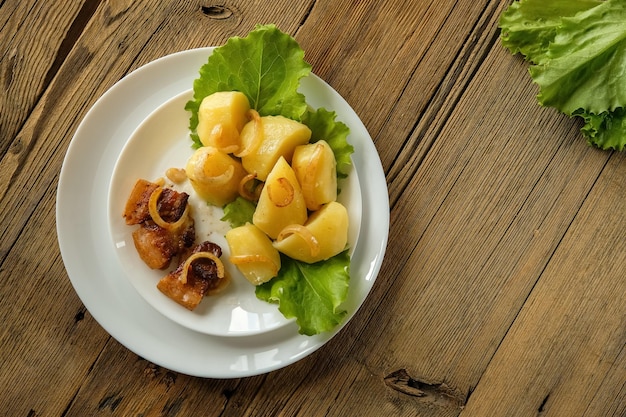 Patatas hervidas con chicharrones comida casera y cocina en una mesa de madera utensilios blancos