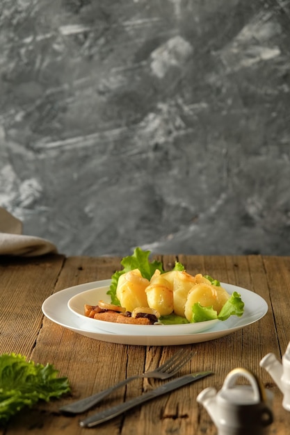 Patatas hervidas con chicharrones comida casera y cocina en una mesa de madera utensilios blancos