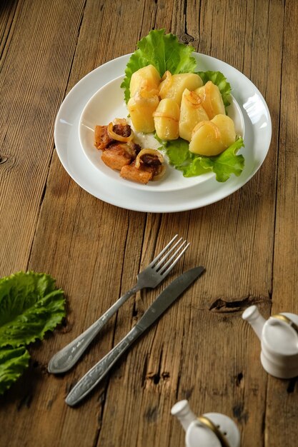 Patatas hervidas con chicharrones comida casera y cocina en una mesa de madera utensilios blancos