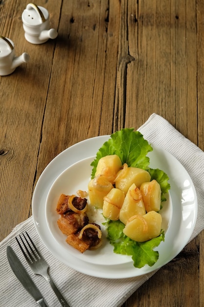 Patatas hervidas con chicharrones comida casera y cocina en una mesa de madera utensilios blancos