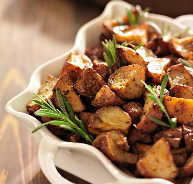 Patatas con hierbas de romero en un plato para hornear blanco cerrar