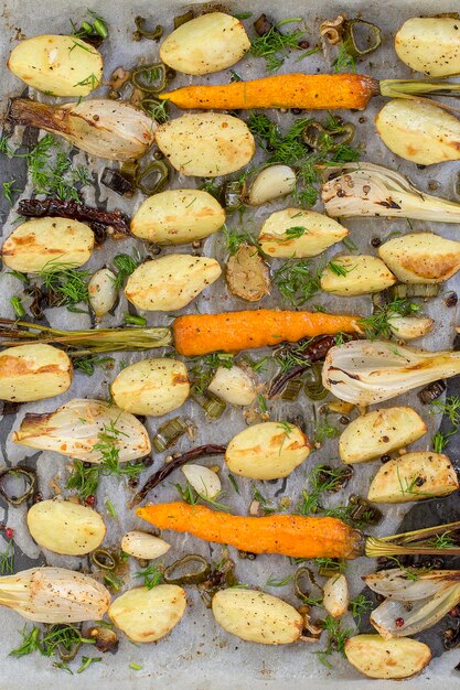 Patatas jóvenes zanahorias cebollas pimientos ajo horneado en el horno Vista superior de cerca