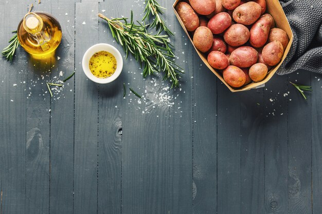 Patatas orgánicas crudas con especias en mesa de madera