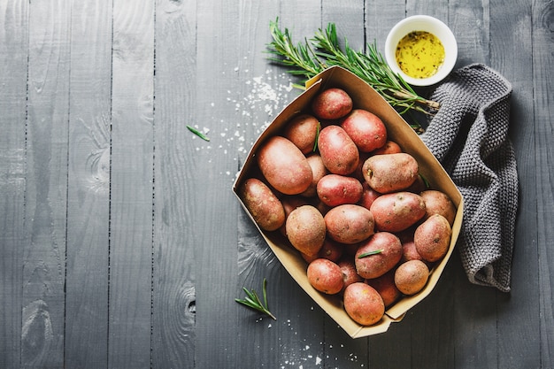 Patatas orgánicas crudas con especias en mesa de madera