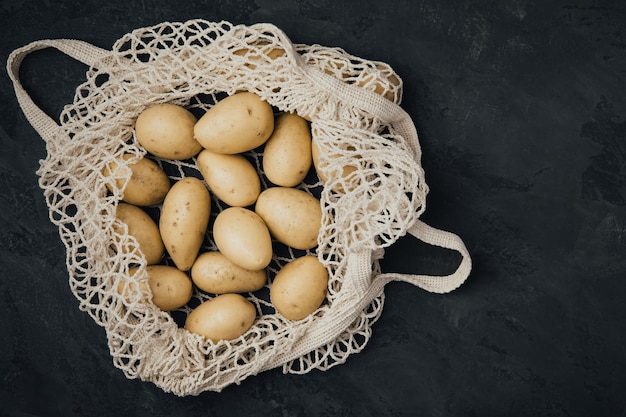 Patatas orgánicas Patatas crudas frescas en bolsa de algodón blanco sobre fondo oscuro vista superior