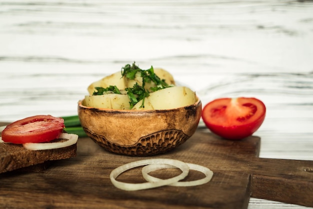 Patatas, pan de centeno, cebolla, tomates y verduras en una mesa blanca 3