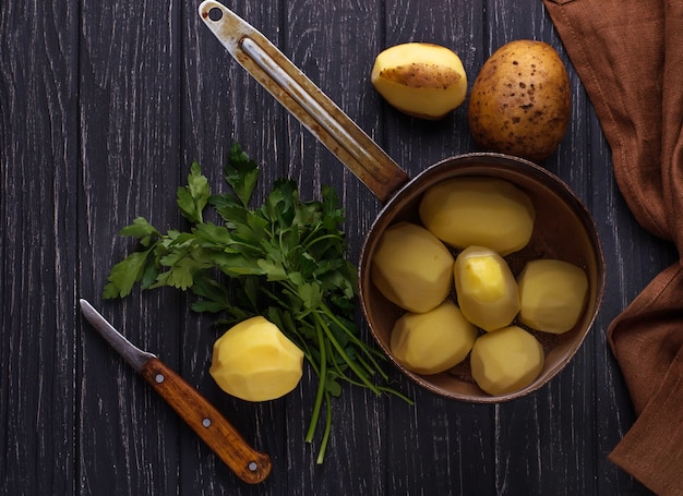 Patatas peladas sin cocer sobre fondo oscuro