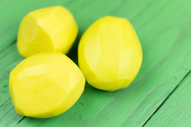 Patatas peladas sobre un fondo de madera verde