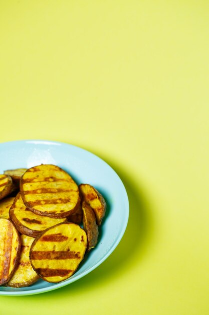 Patatas a la plancha hasta que estén doradas en una placa azul sobre fondo amarillo