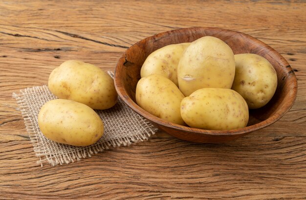 Patatas en un recipiente sobre la mesa de madera.