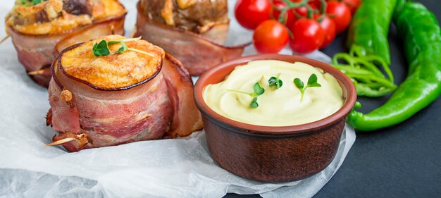 Patatas rellenas al horno con queso envuelto en tocino sobre una mesa oscura. De cerca. Bandera.