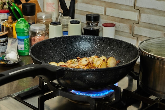 Las patatas en rodajas se fríen en una sartén sobre una estufa de gas