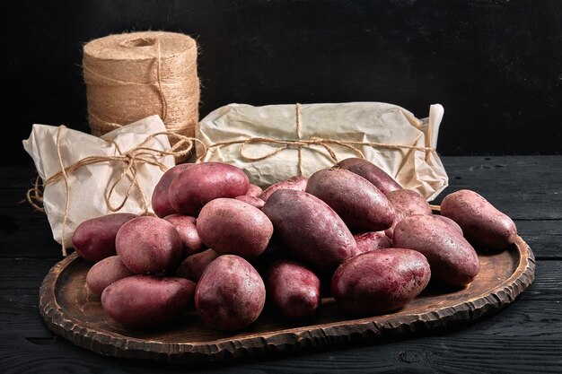 Patatas rojas sobre un fondo de madera oscura Concepto de entrega de alimentos, envases ecológicos