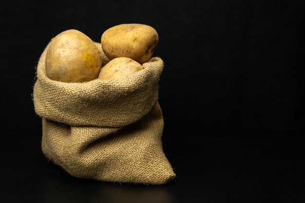 Foto patatas sobre un fondo negro, bolsa de patatas