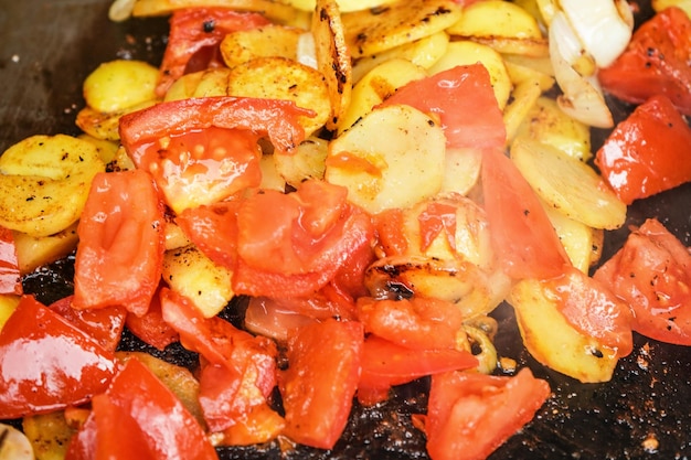 Patatas y tomates cortados en trozos pequeños asados a la parrilla eléctrica, detalle de cierre