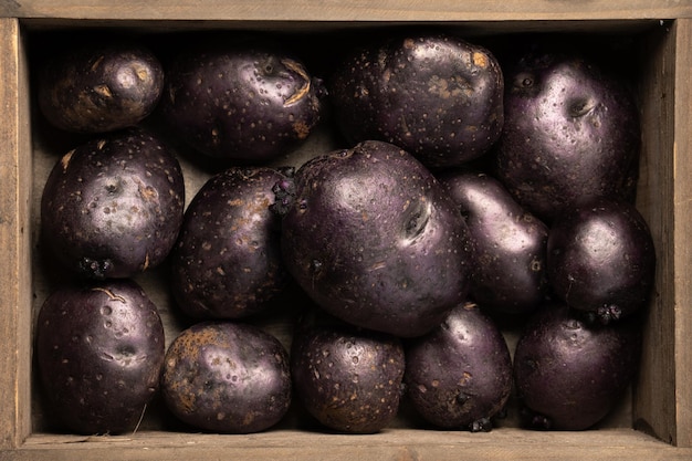 Patatas violetas vitelotte crudas en caja de madera Vista superior