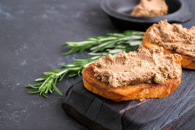 Patê de carne caseiro no pão duro tostado. estilo de foto escura.