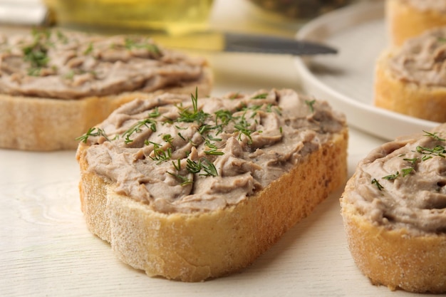 Patê de fígado de frango caseiro fresco com ervas para pão em uma mesa de madeira branca. Uma sandes. fechar-se