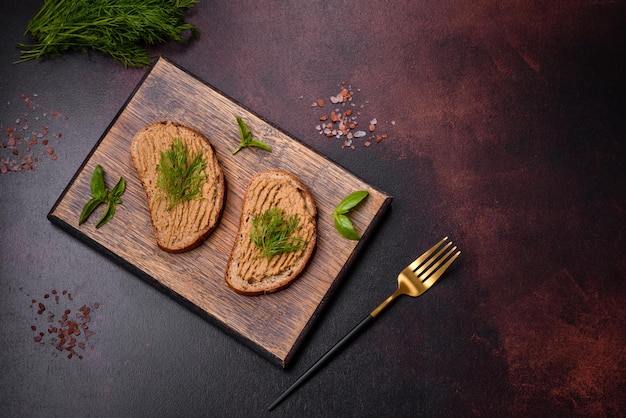 Patê de fígado de lanche de carne caseiro com torradas em um fundo escuro de concreto