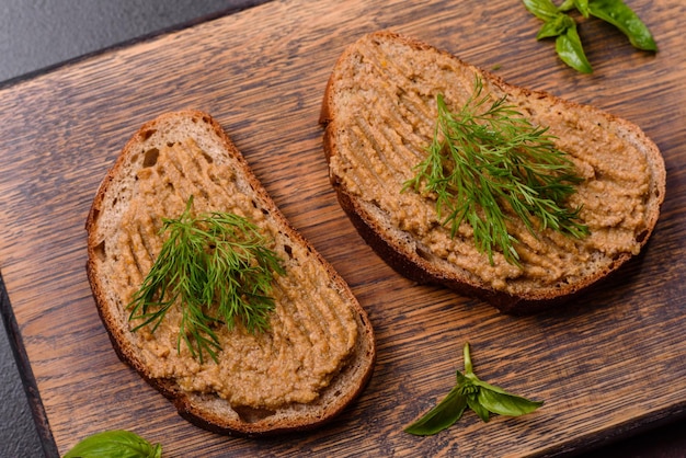 Paté de hígado de bocadillo de carne casero con tostadas sobre un fondo de hormigón oscuro