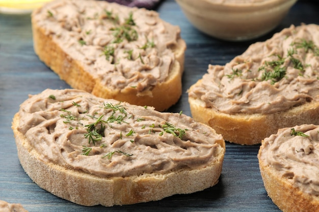 Paté de hígado de pollo casero fresco con hierbas en pan sobre una mesa de madera azul. Un sándwich. de cerca