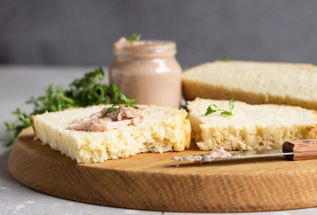 Paté de hígado de pollo casero fresco en pan con tomillo en una tabla para cortar madera.