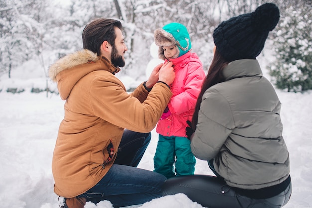 Paternidade, moda, estação e conceito dos povos - a família feliz com a criança no inverno veste-se fora