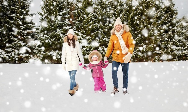 paternidade, moda, temporada e conceito de pessoas - família feliz com criança em roupas de inverno caminhando ao ar livre