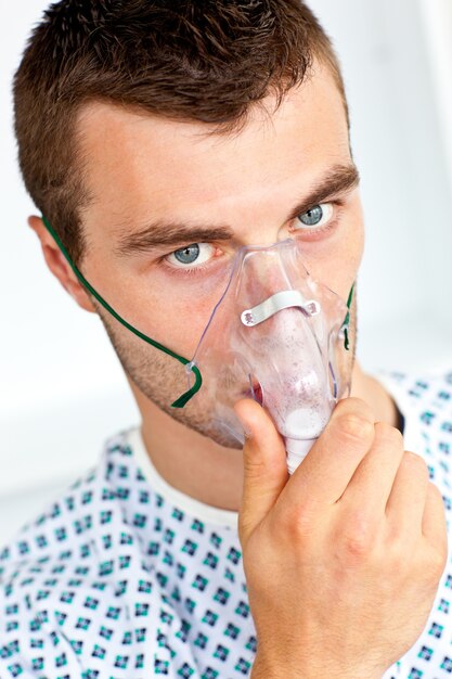 Patient, der die Grippe trägt eine Maske hat und die Kamera betrachtet