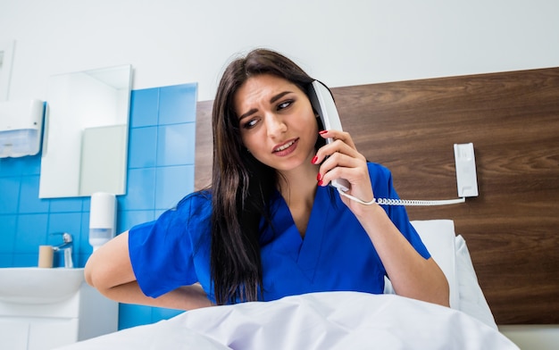 Patient, der im Krankenhausbett am Telefon spricht. Junge kaukasische Frau.