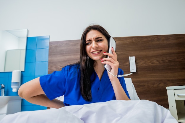 Patient, der im Krankenhausbett am Telefon spricht. Junge kaukasische Frau.