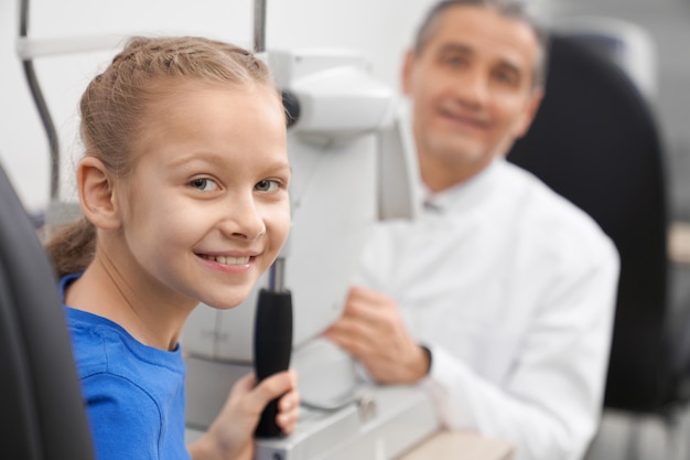 Patient, Mädchen, das mit Arzt in Optikerbüro aufwirft.